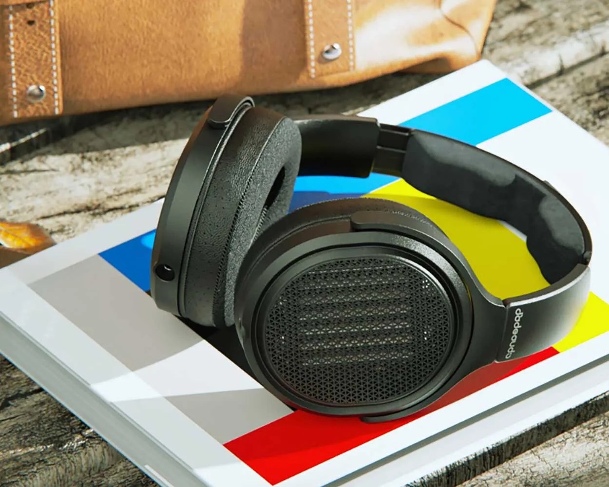 Black over-ear headphones with mesh ear cups resting on a colorful geometric-patterned book.