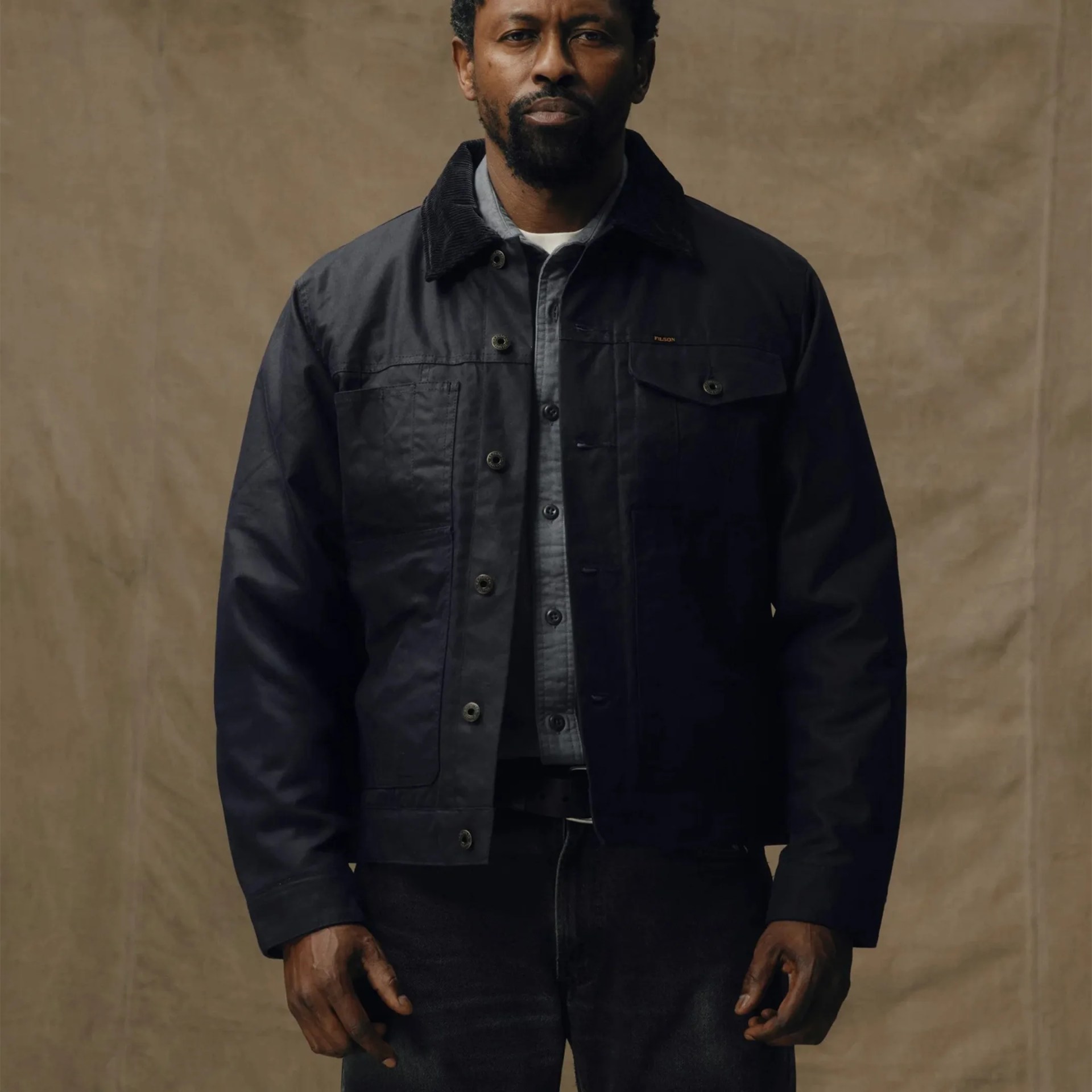 Black button-up jacket with corduroy collar worn over a gray shirt.