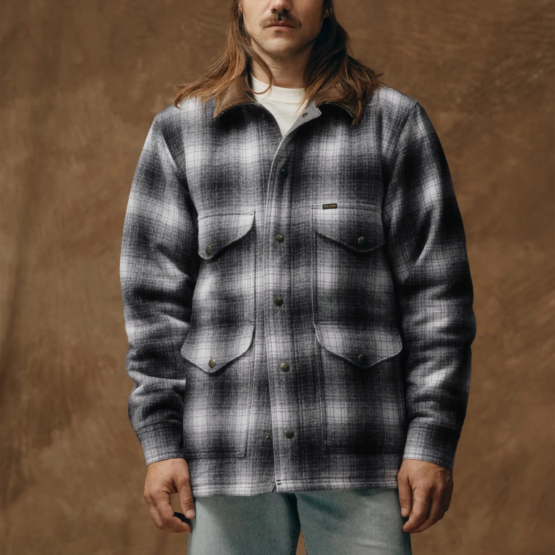 Black and white plaid jacket with brown corduroy collar and four front flap pockets worn by a person.