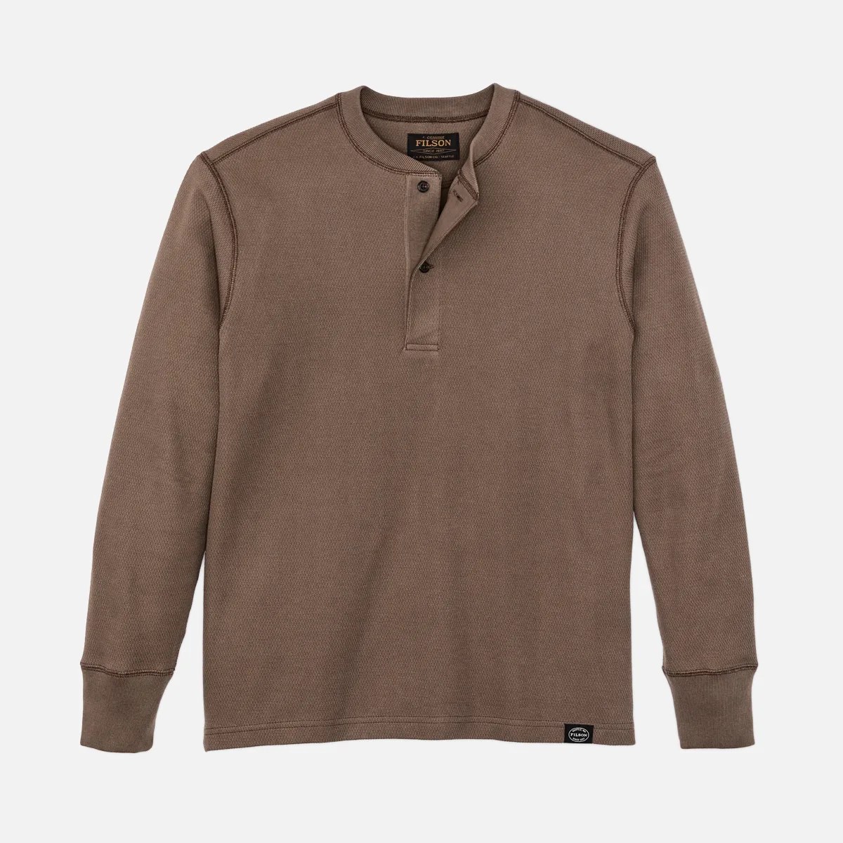 Brown long-sleeve henley shirt with two buttons and a small black Filson logo patch near the hem.