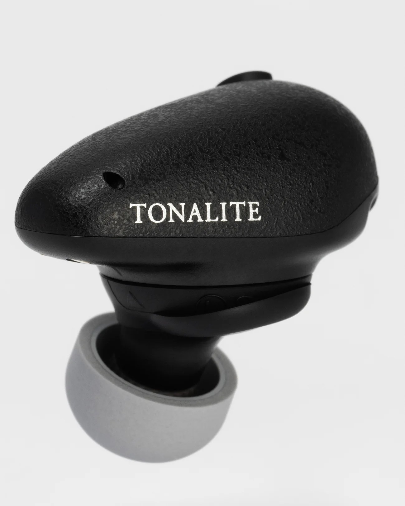 Black wireless earbud with textured finish and white "TONALITE" branding, featuring a gray silicone ear tip.