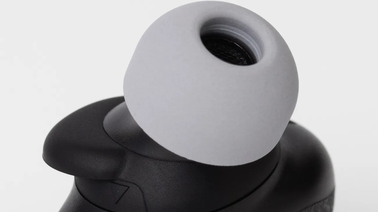 Close-up of a black wireless earbud with a gray silicone ear tip.
