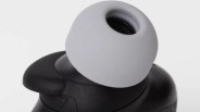 Close-up of a black wireless earbud with a gray silicone ear tip.