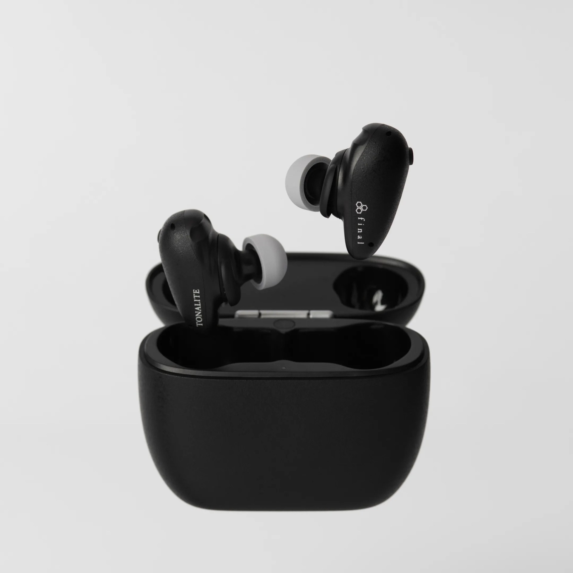 Black wireless earbuds with white silicone tips floating above an open black charging case.