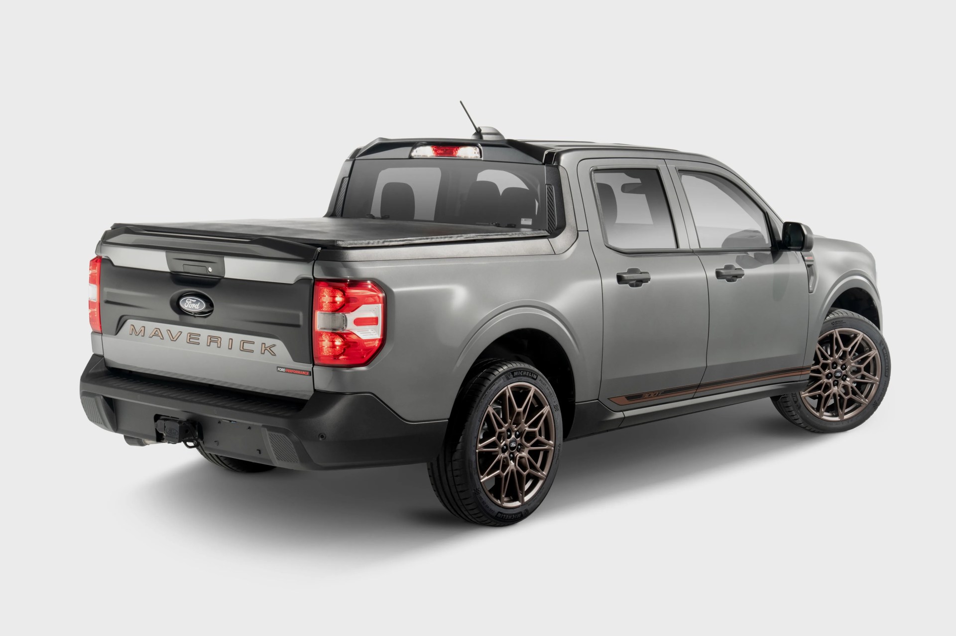 Gray Ford Maverick pickup truck with bronze wheels and a covered bed, shown from rear side angle.