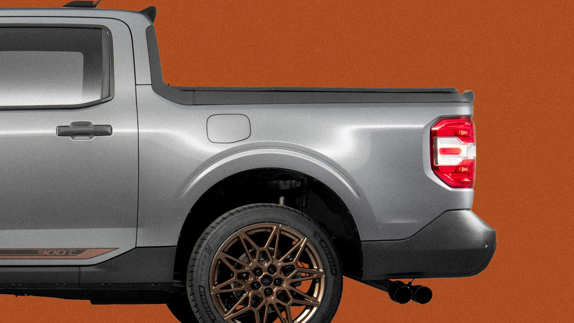 Rear side view of a silver pickup truck with bronze multi-spoke wheels and red tail light on an orange background.
