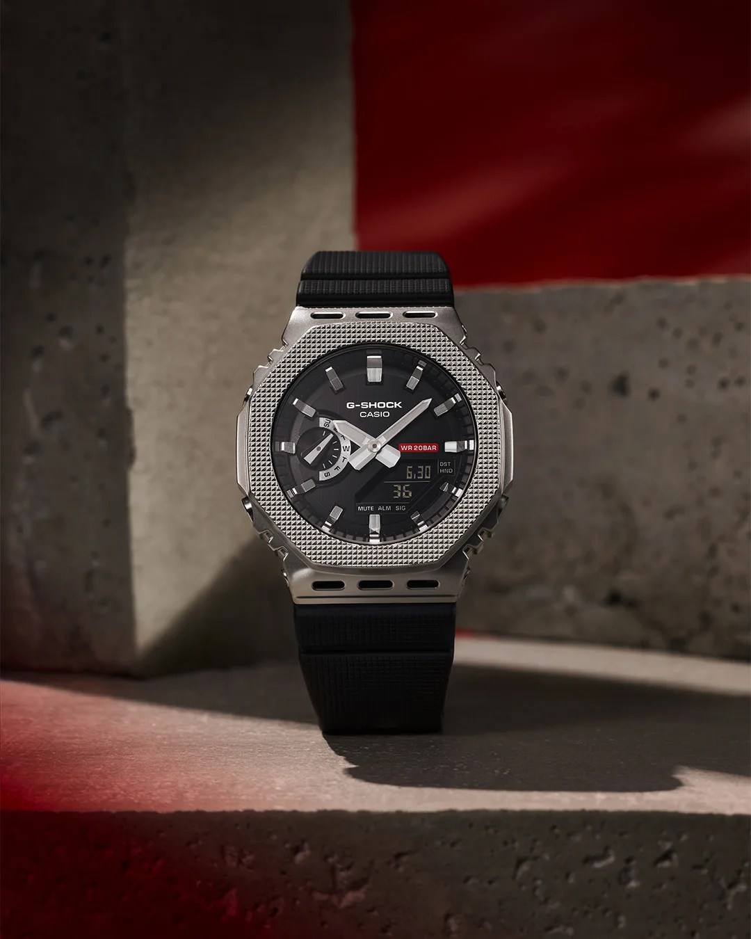 Black and silver Casio G-Shock watch with textured bezel and digital-analog display on a concrete surface.