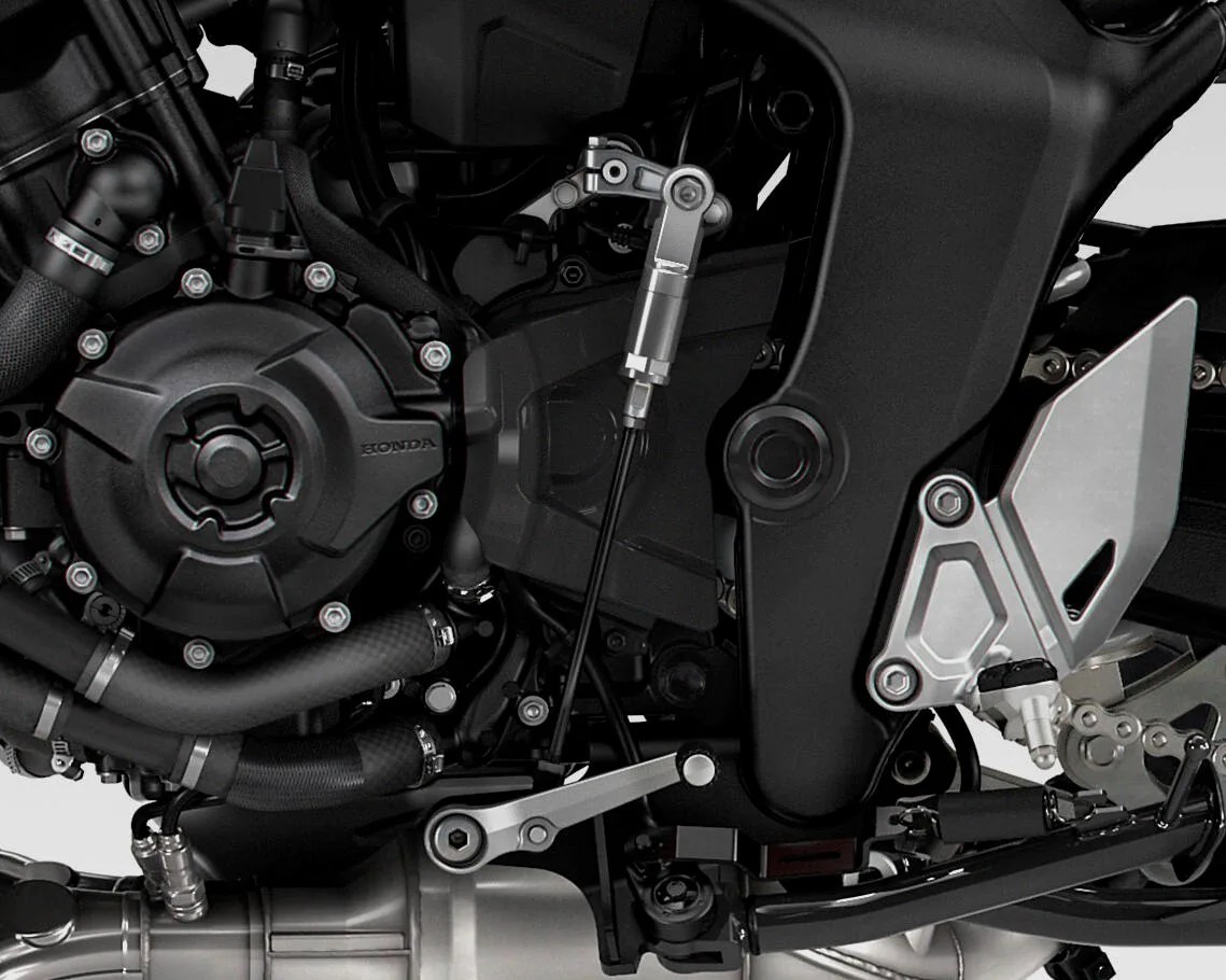 Close-up of a black Honda motorcycle engine with visible hoses, bolts, and silver footpeg bracket.
