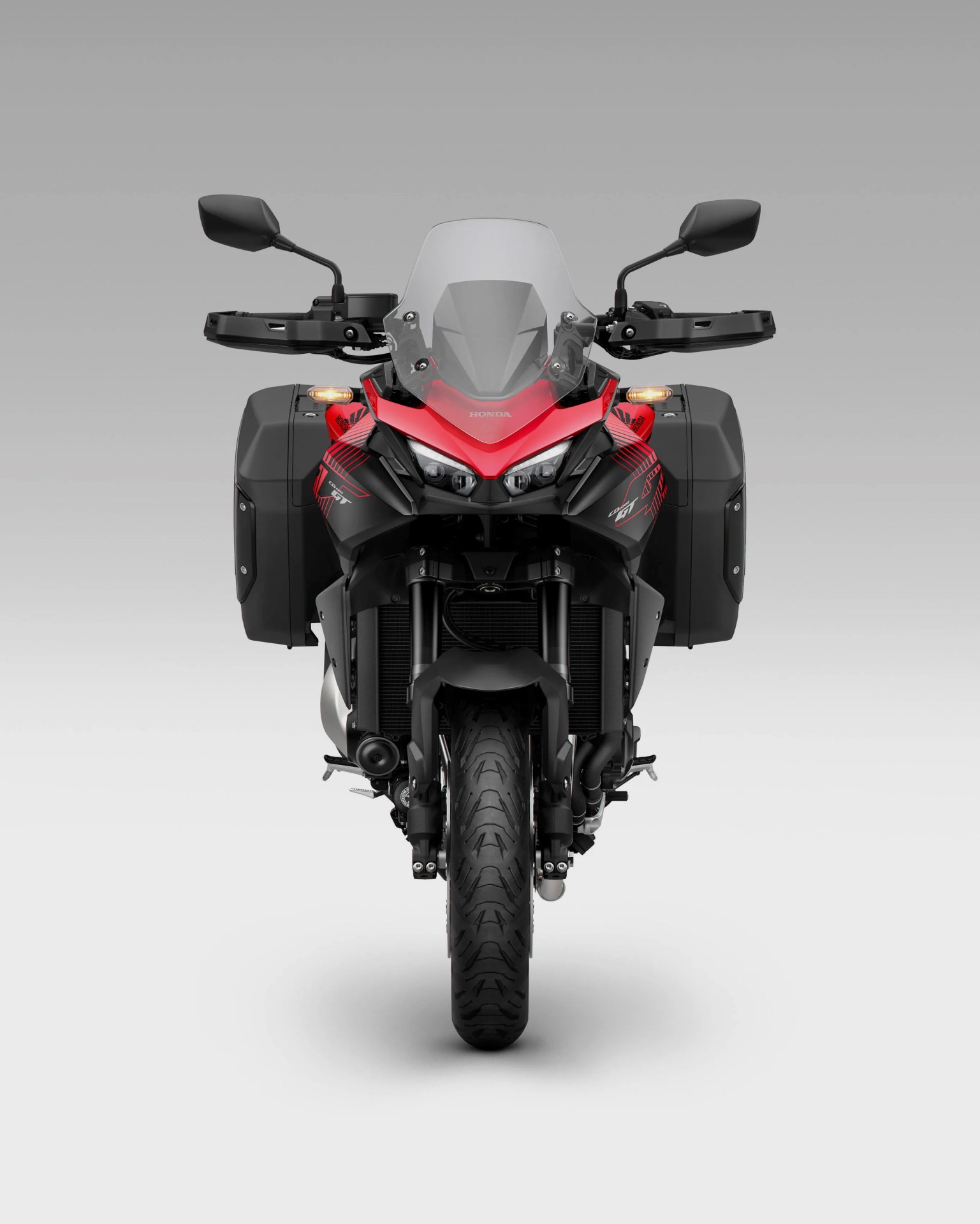 Front view of a red and black Honda touring motorcycle with side panniers and a clear windshield.