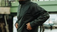 Dark green water-resistant jacket with a high collar worn by a person near a waterfront.