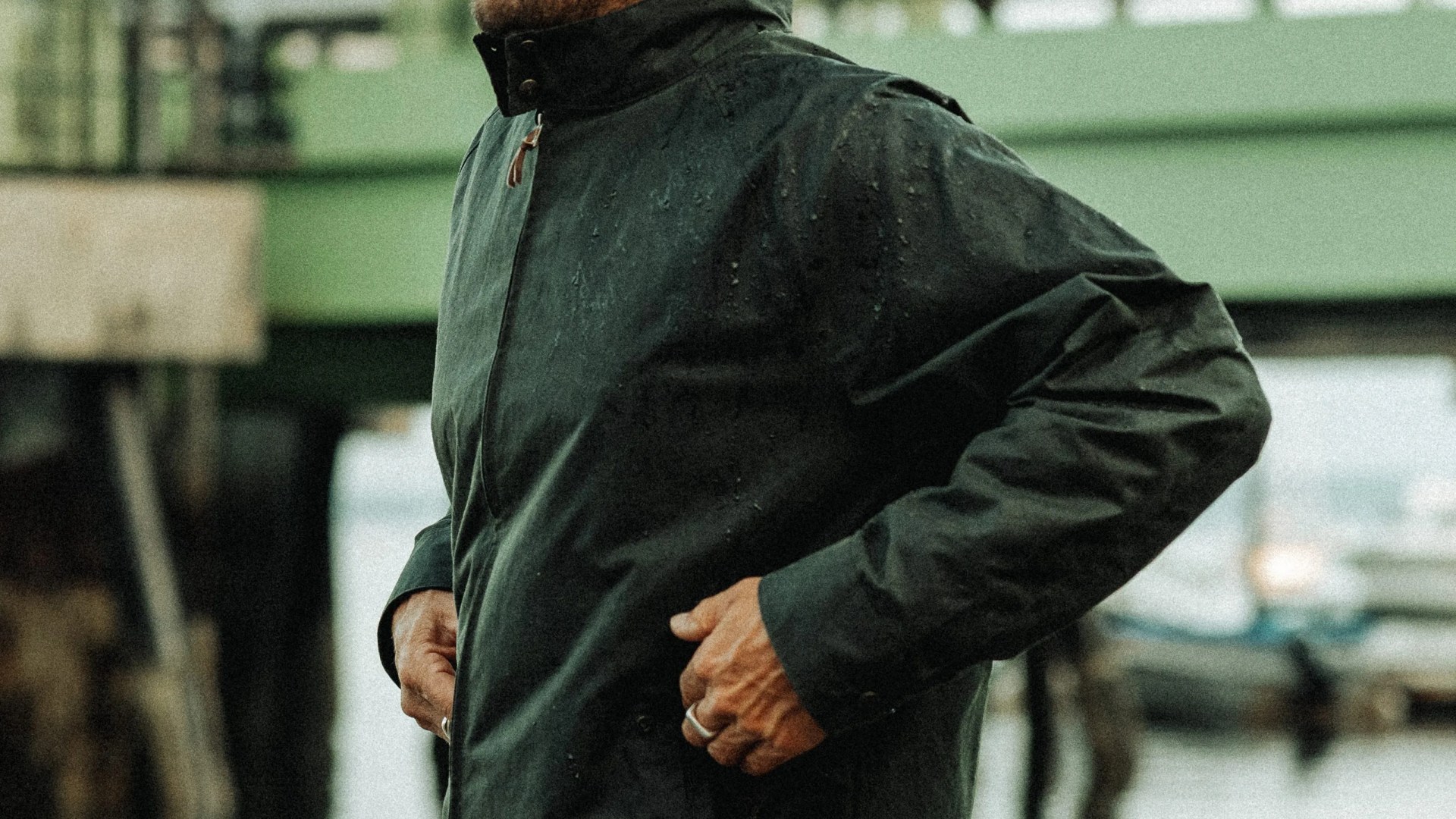 Dark green water-resistant jacket with a high collar worn by a person near a waterfront.