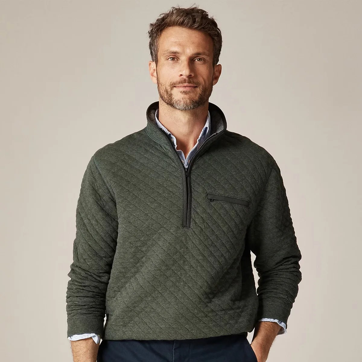 Dark green quilted half-zip pullover with a zippered chest pocket worn over a striped shirt.