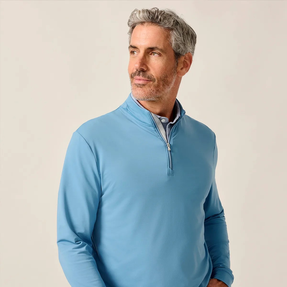 Man wearing a light blue quarter-zip pullover over a collared shirt against a plain background.