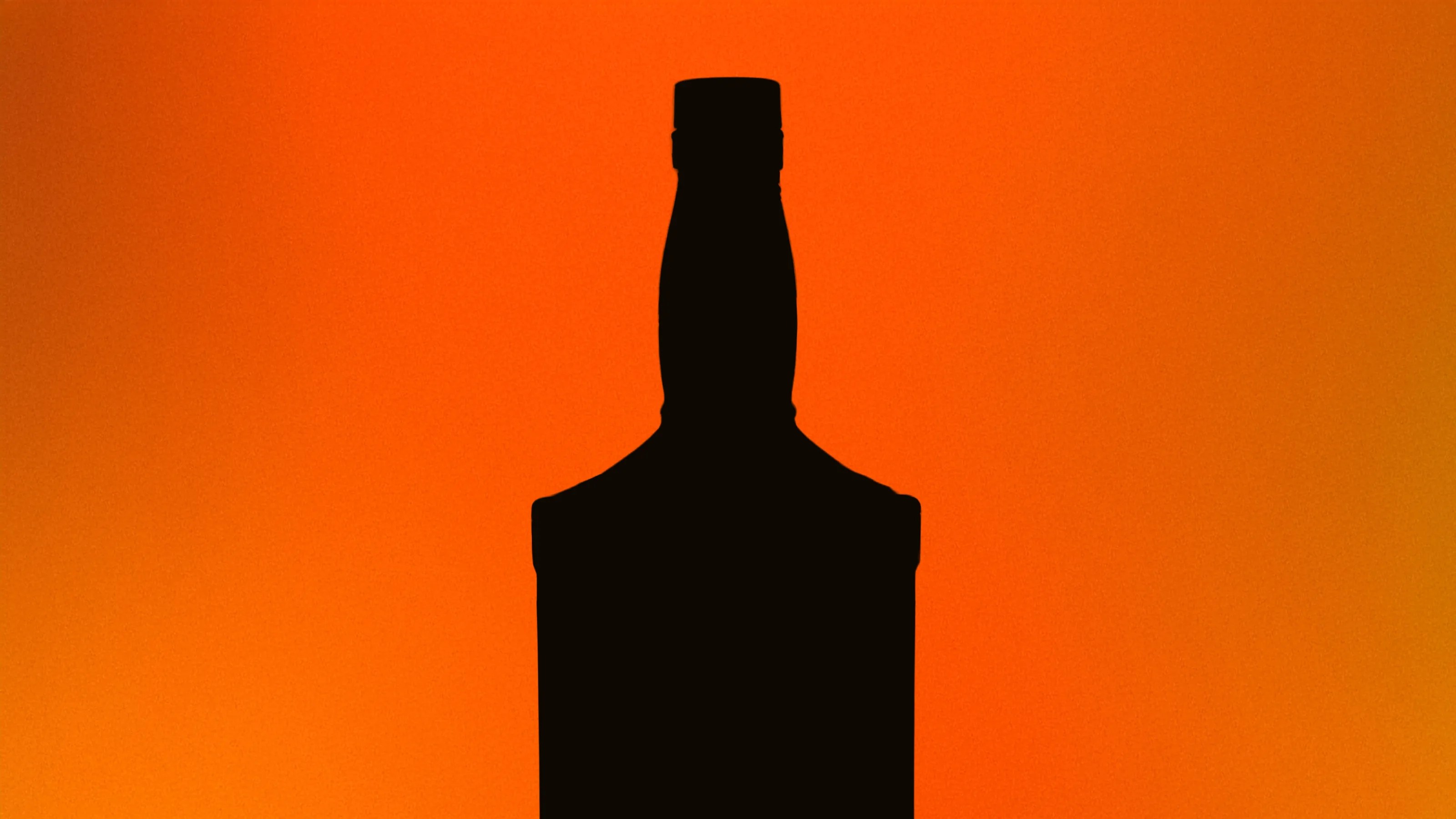 Silhouette of a bottle with a narrow neck and cap against an orange gradient background.