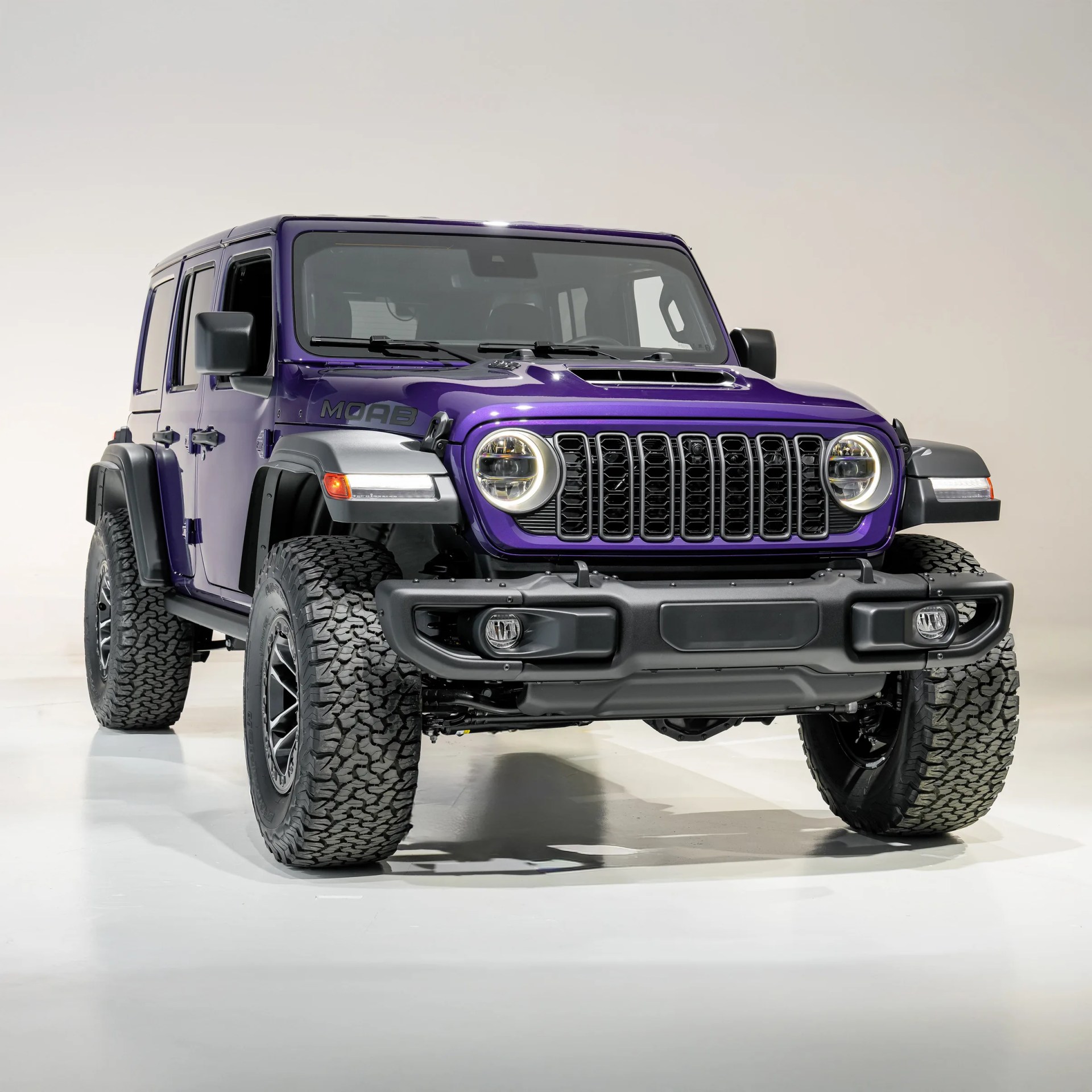 Purple Jeep Wrangler Moab edition with large off-road tires in a studio setting.