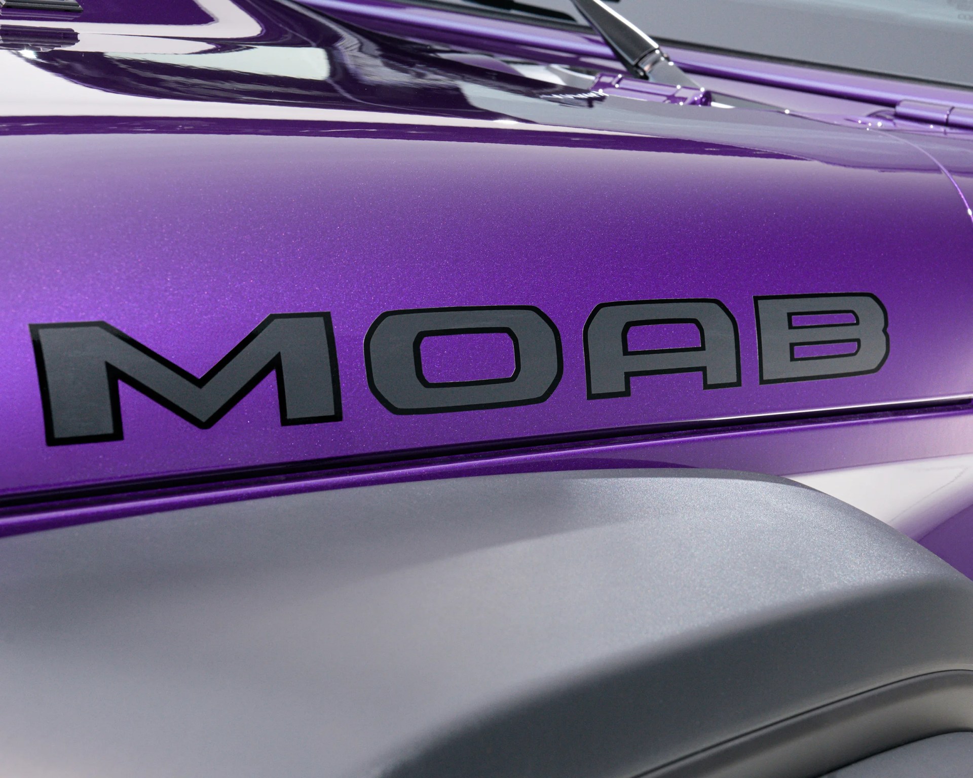 Glossy purple vehicle panel with large black "MOAB" lettering and a matte gray fender below.