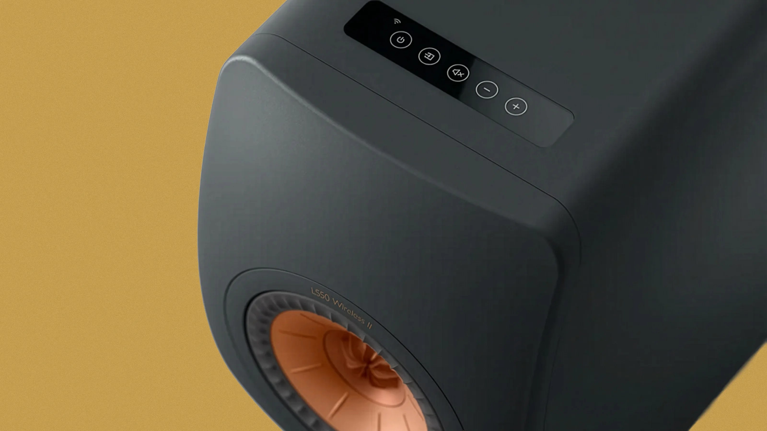 Black wireless speaker with copper-colored cone and control buttons on top against a mustard background.