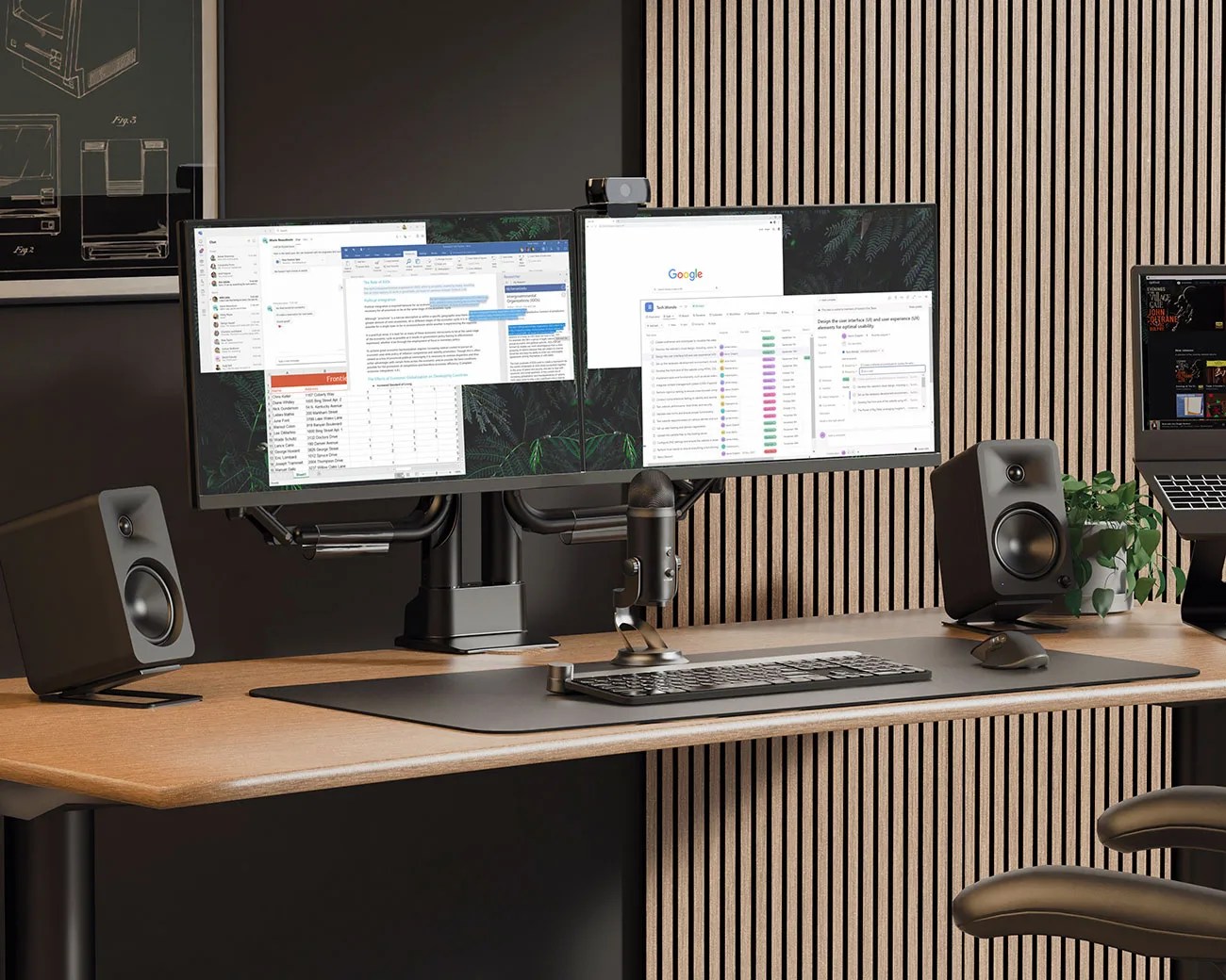 Dual widescreen monitors on a black stand with a microphone, keyboard, mouse, and black speakers on a wooden desk.