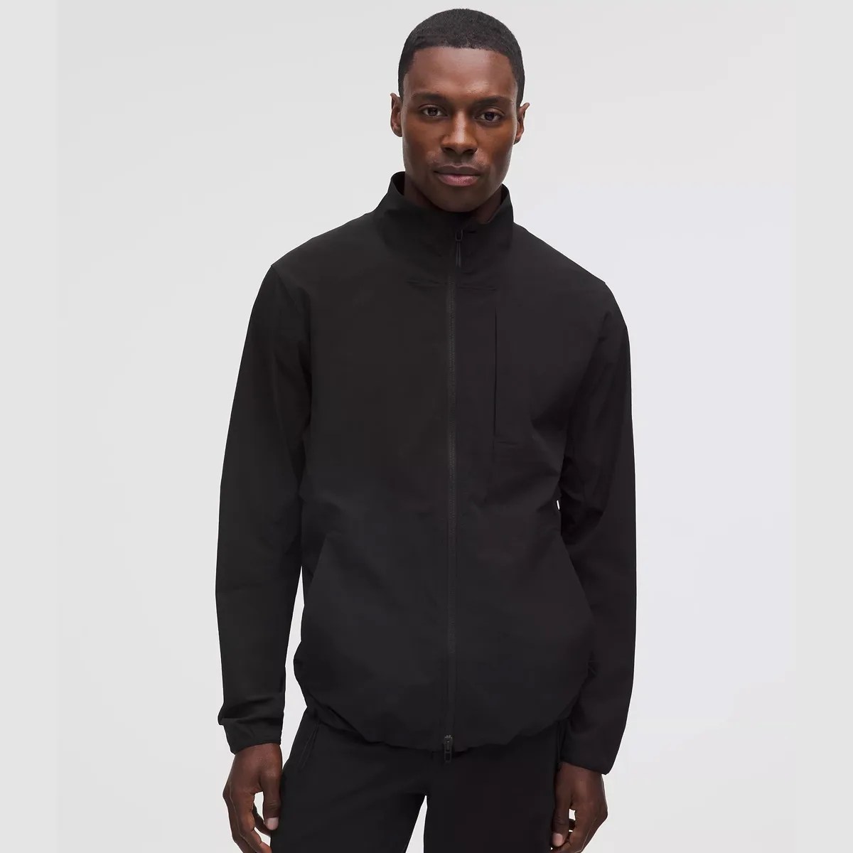 Black zip-up jacket with high collar worn by a person against a plain light background.