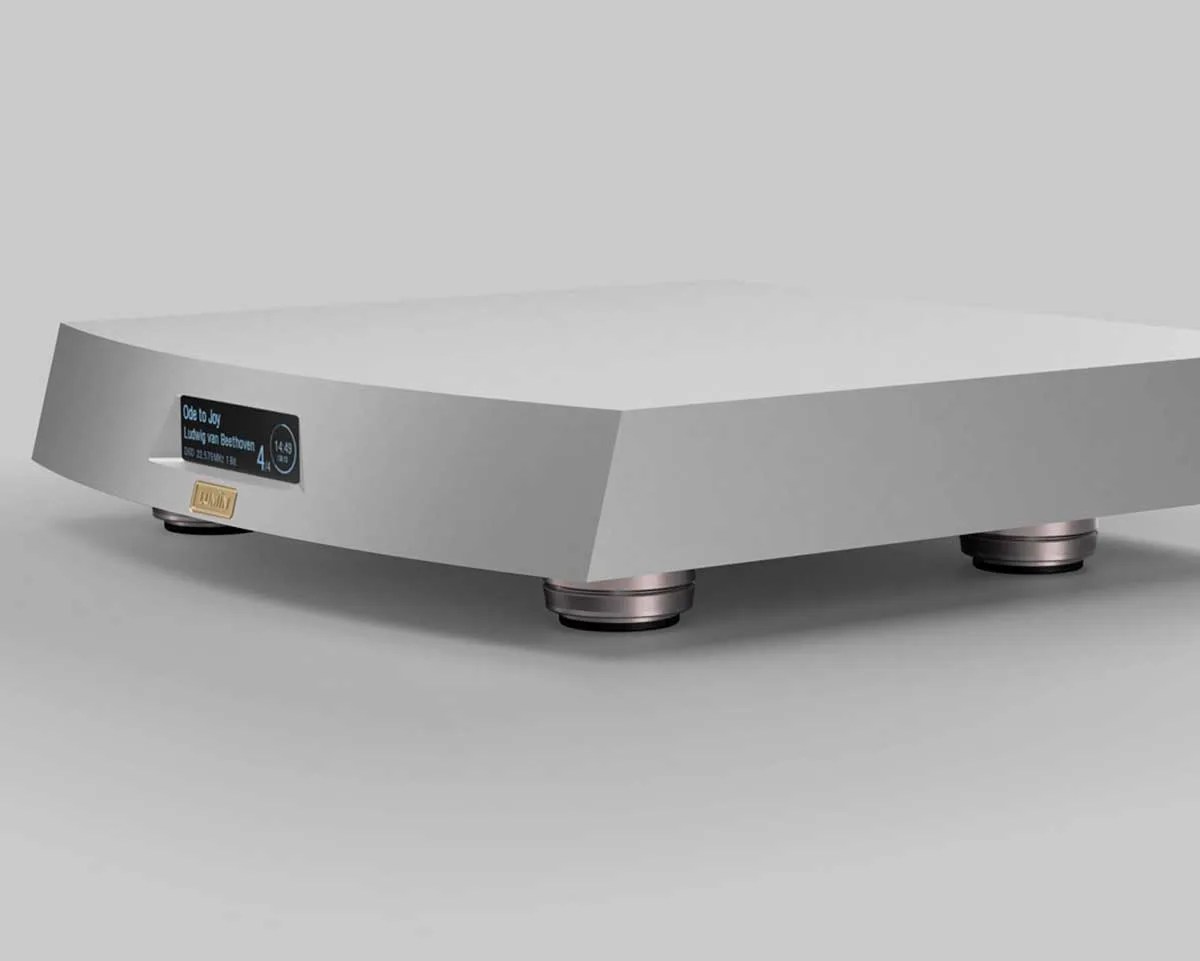 Matte silver rectangular audio device with a small digital display showing music track info and round metallic feet.