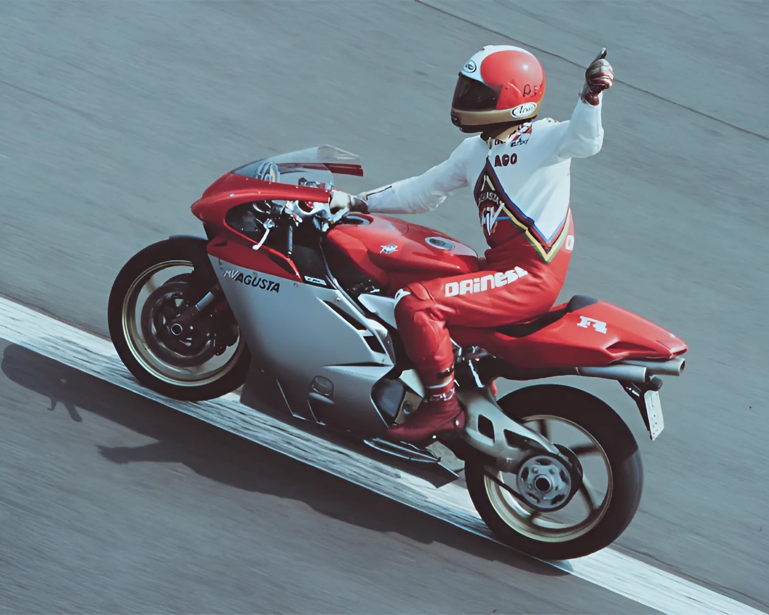 Red and silver MV Agusta F4 motorcycle with rider in red and white gear giving a thumbs-up on a racetrack.