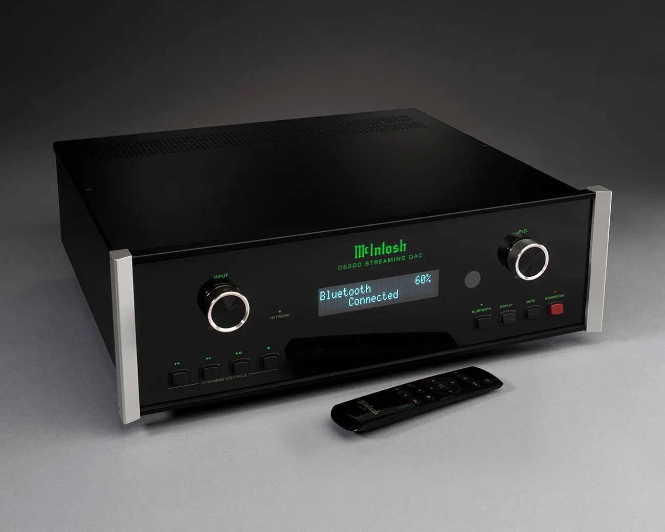 Black McIntosh DS200 streaming DAC with digital display showing "Bluetooth Connected" and a remote control on a gray surface.