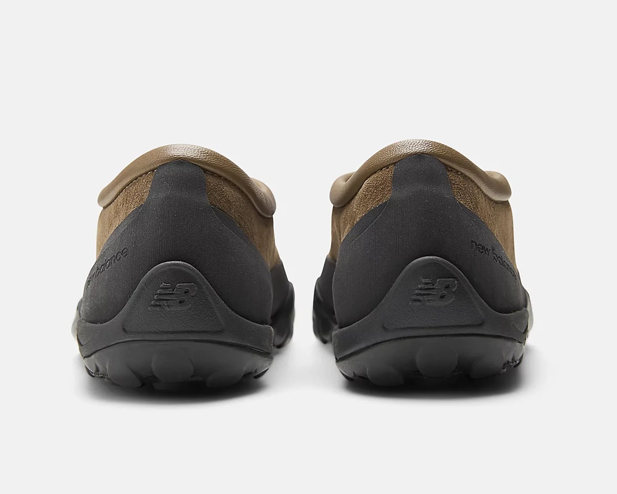 Pair of brown suede and black rubber slip-on shoes shown from the back on a white background.