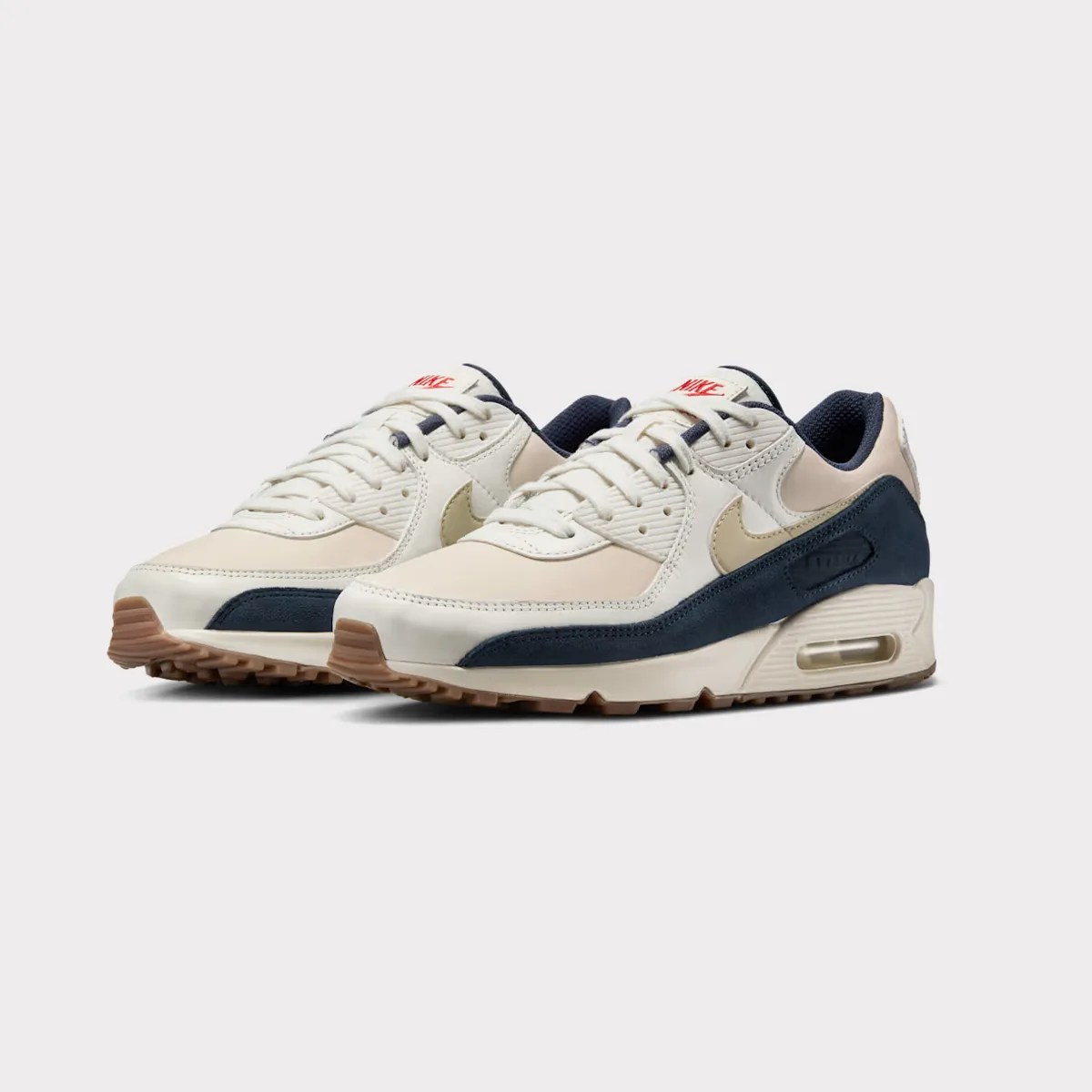 Pair of beige and navy Nike Air Max sneakers with gum soles on a white background.