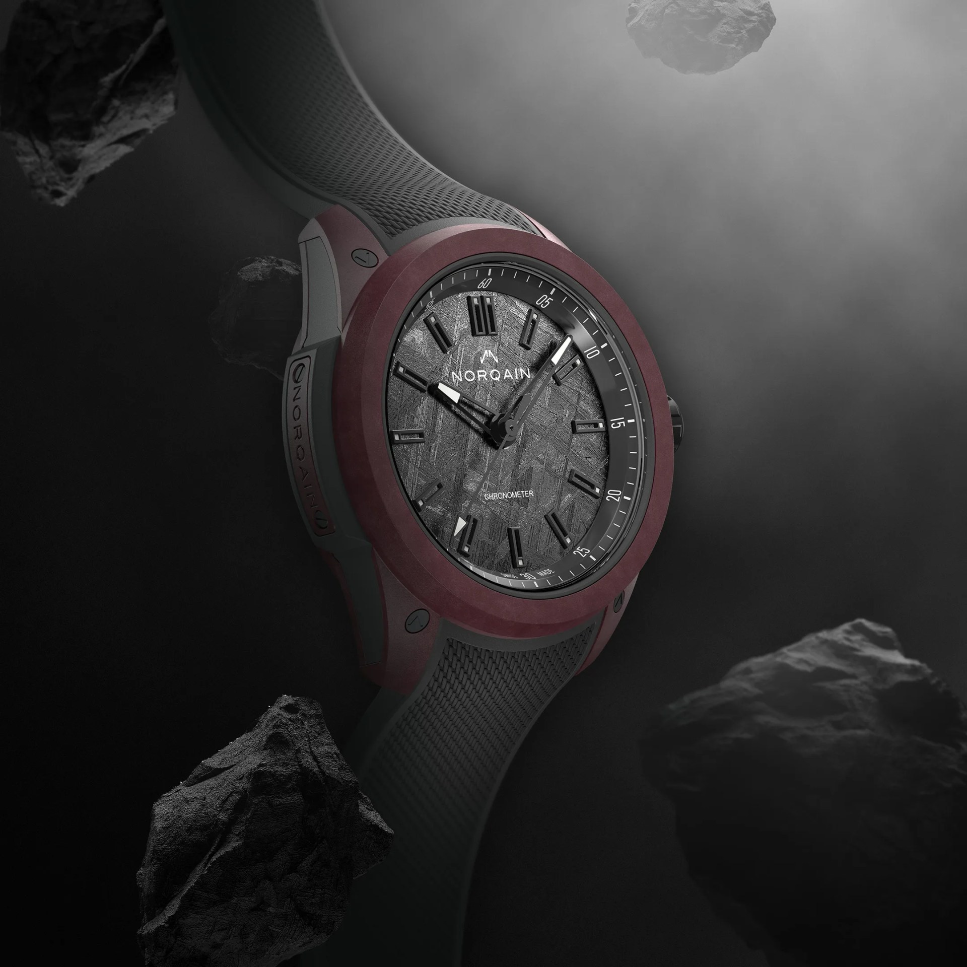 Norqain wristwatch with meteorite dial, black hour markers, and maroon bezel on a black rubber strap.