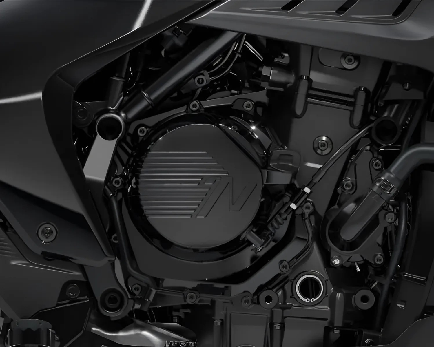 Close-up of a black motorcycle engine with a circular cover featuring a stylized "N" logo and visible bolts and cables.