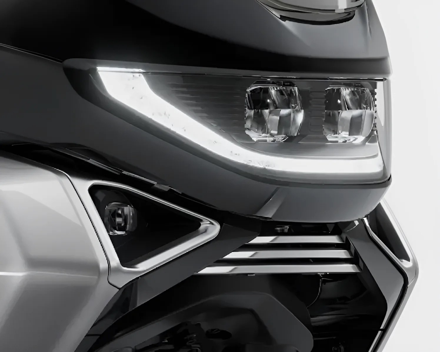 Close-up of a black and silver motorcycle front with dual headlights and LED strip lights.