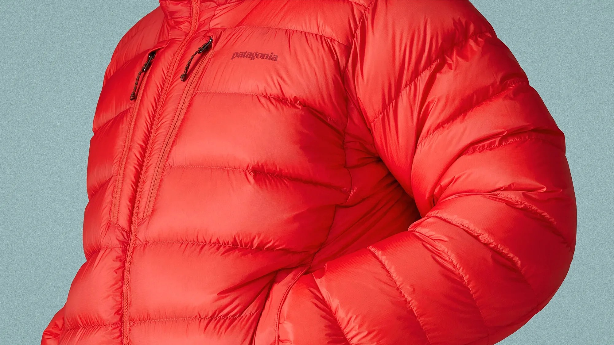 Red Patagonia puffer jacket with chest and side zip pockets against a light blue background.