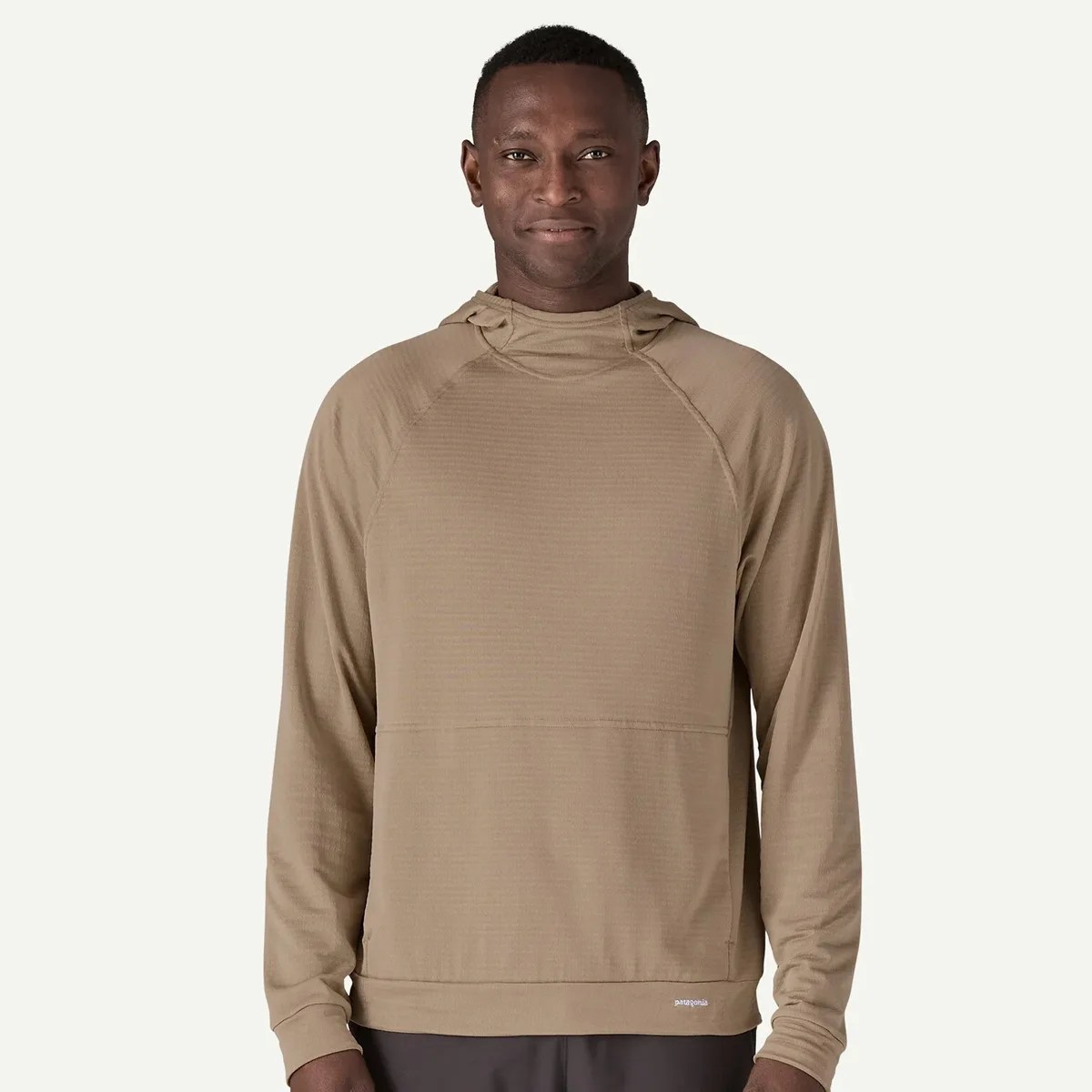 Light brown long-sleeve hooded pullover with a small Patagonia logo near the hem worn by a person.