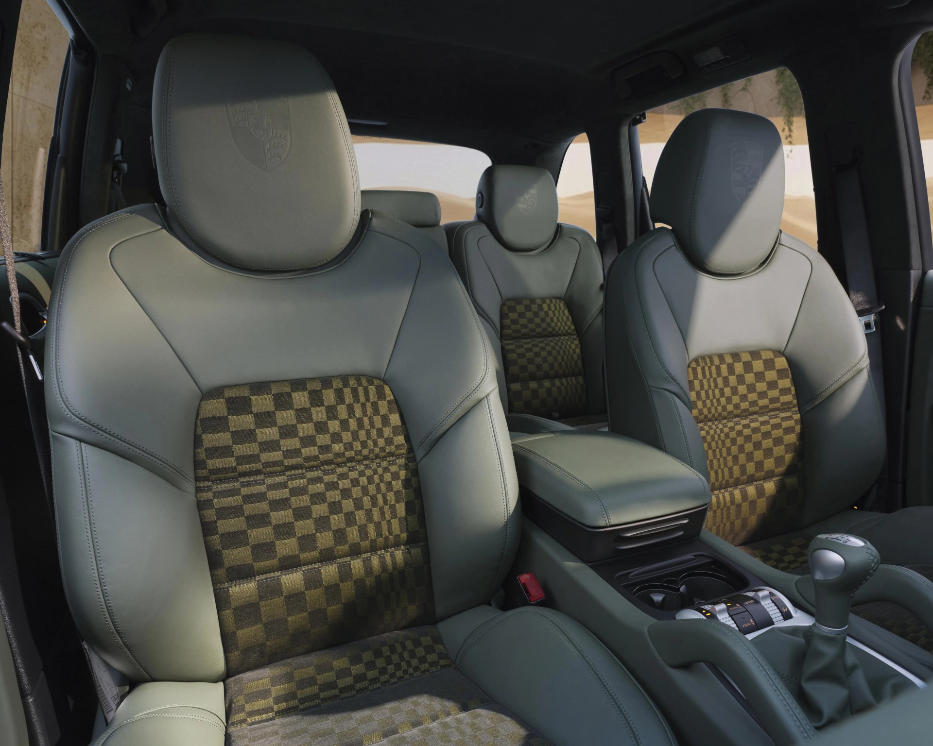 Green leather car seats with checkered fabric inserts and embossed headrests inside a vehicle.