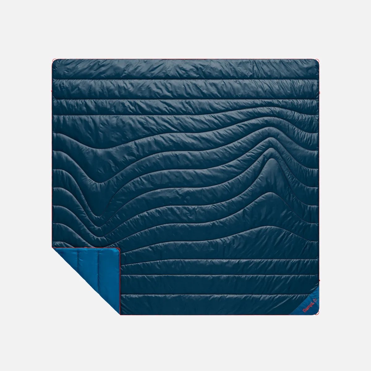 Dark blue quilted blanket with wavy stitching and a folded corner showing lighter blue underside.