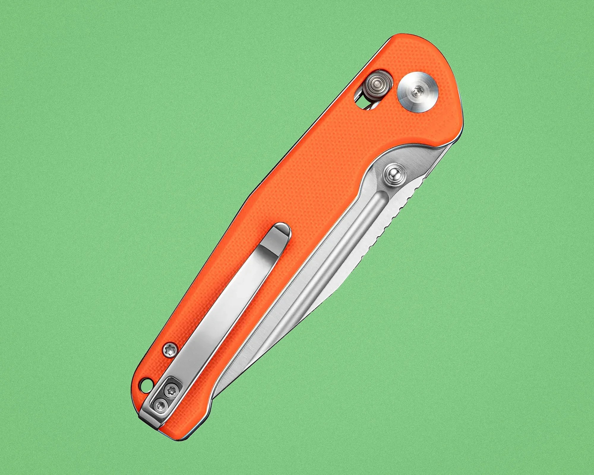 Orange folding pocket knife with partially serrated stainless steel blade and metal clip on a green background.