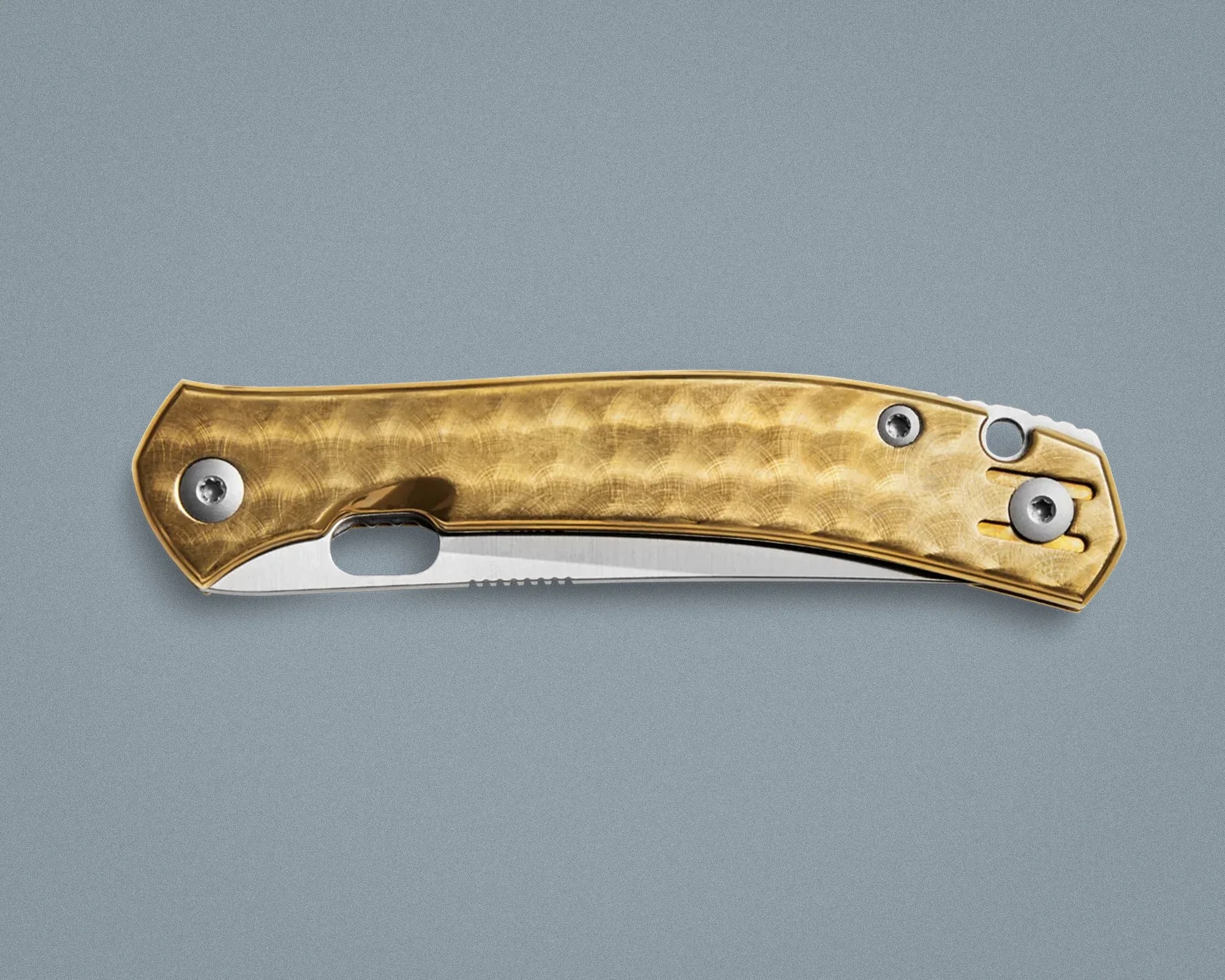 Folding pocket knife with a textured gold handle and partially visible stainless steel blade on a gray surface.