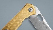 Close-up of a folding knife with a textured tan handle and a partially serrated stainless steel blade labeled "GIANT MOUSE M390.