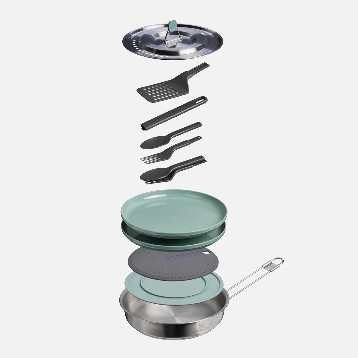 Camping cookware set with stainless steel pan, green plates, black utensils, and a metal lid.