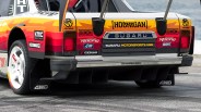 Rear view of a Subaru race car with colorful orange, red, and yellow gradient livery and multiple sponsor decals.