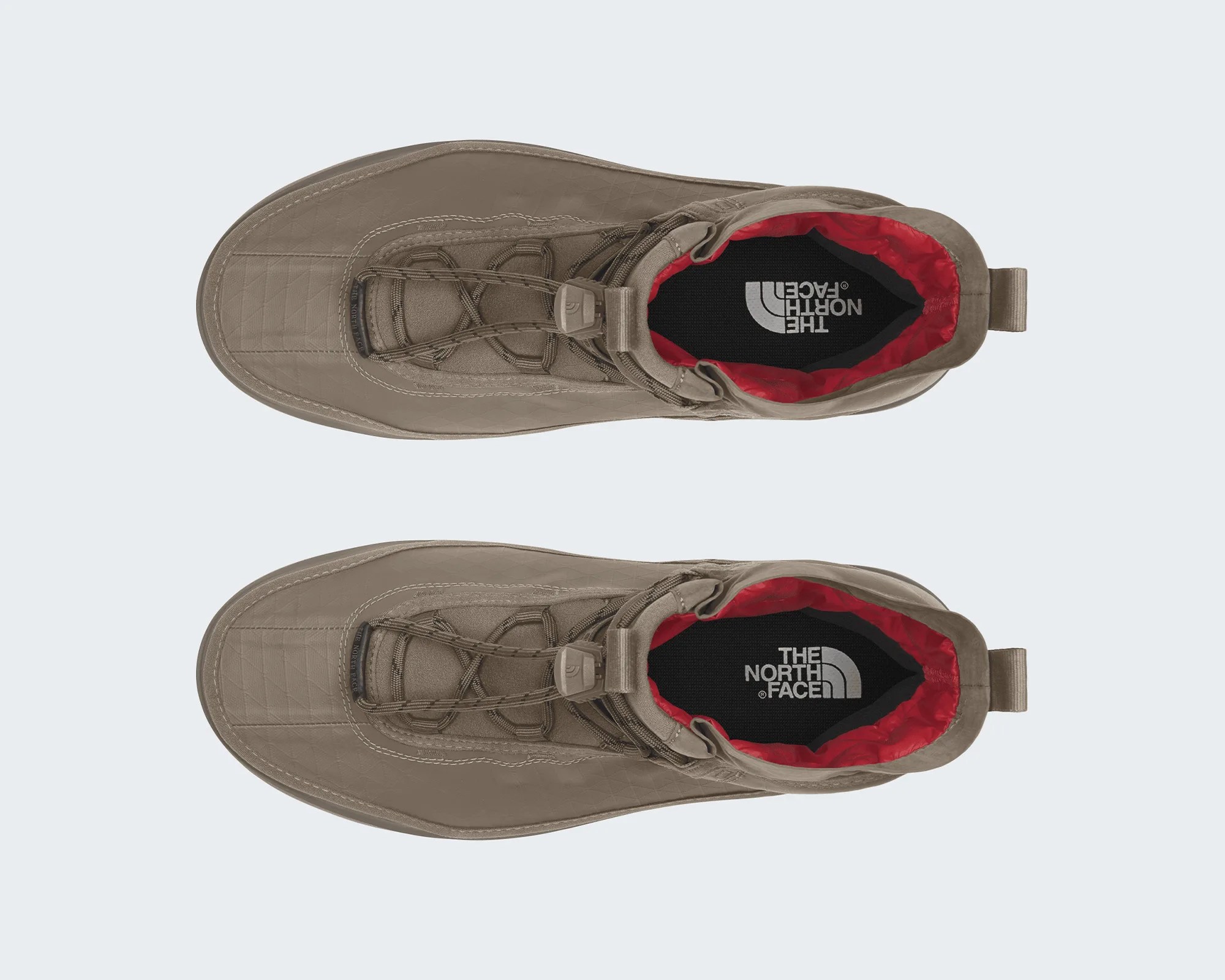 Pair of taupe The North Face boots with red inner lining and black insoles, viewed from above.