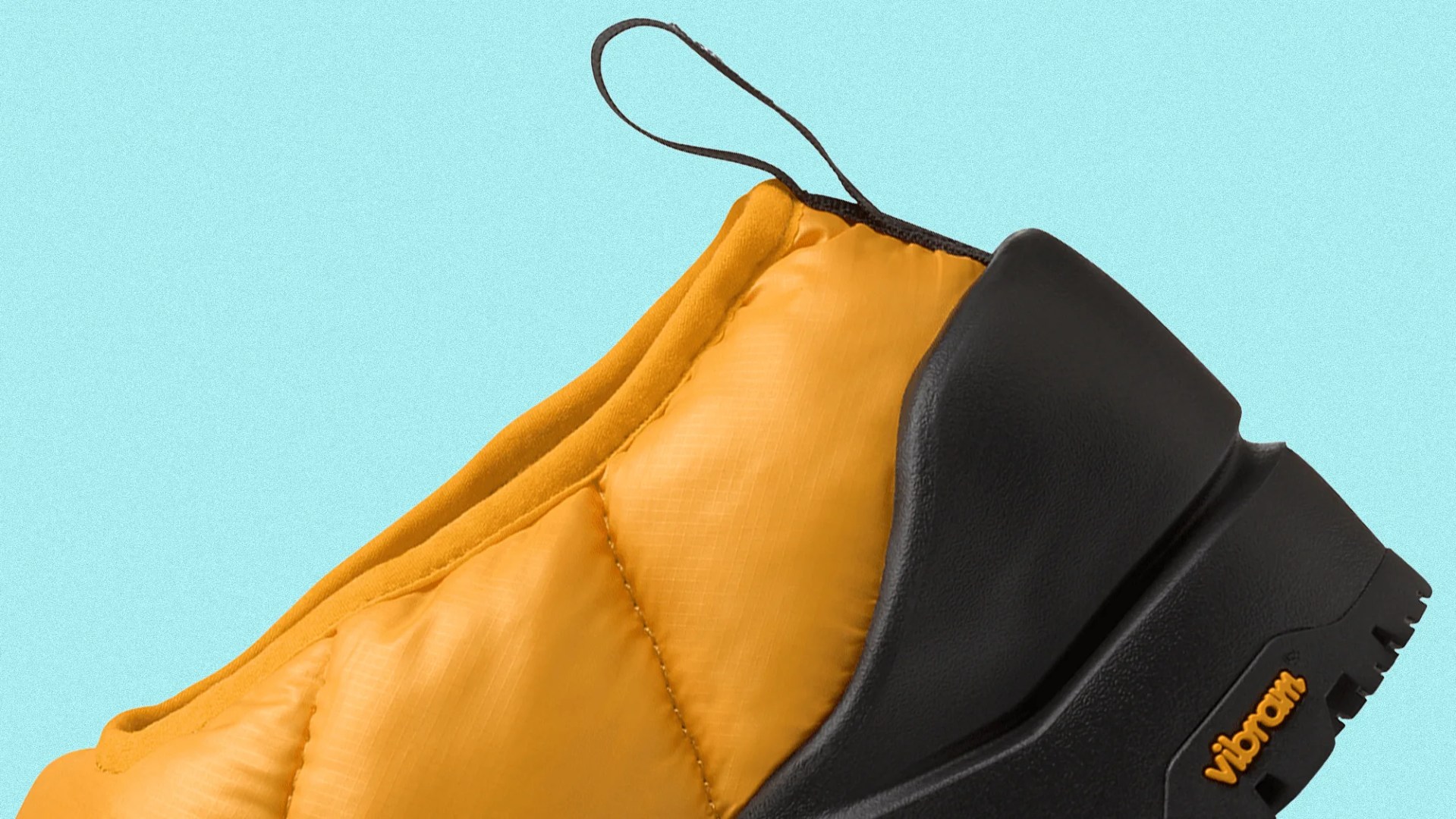 Close-up of a yellow quilted fabric shoe upper with a black Vibram sole and a black pull loop.