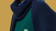Dark blue ribbed knit scarf draped over a green sweater with a small embroidered design.