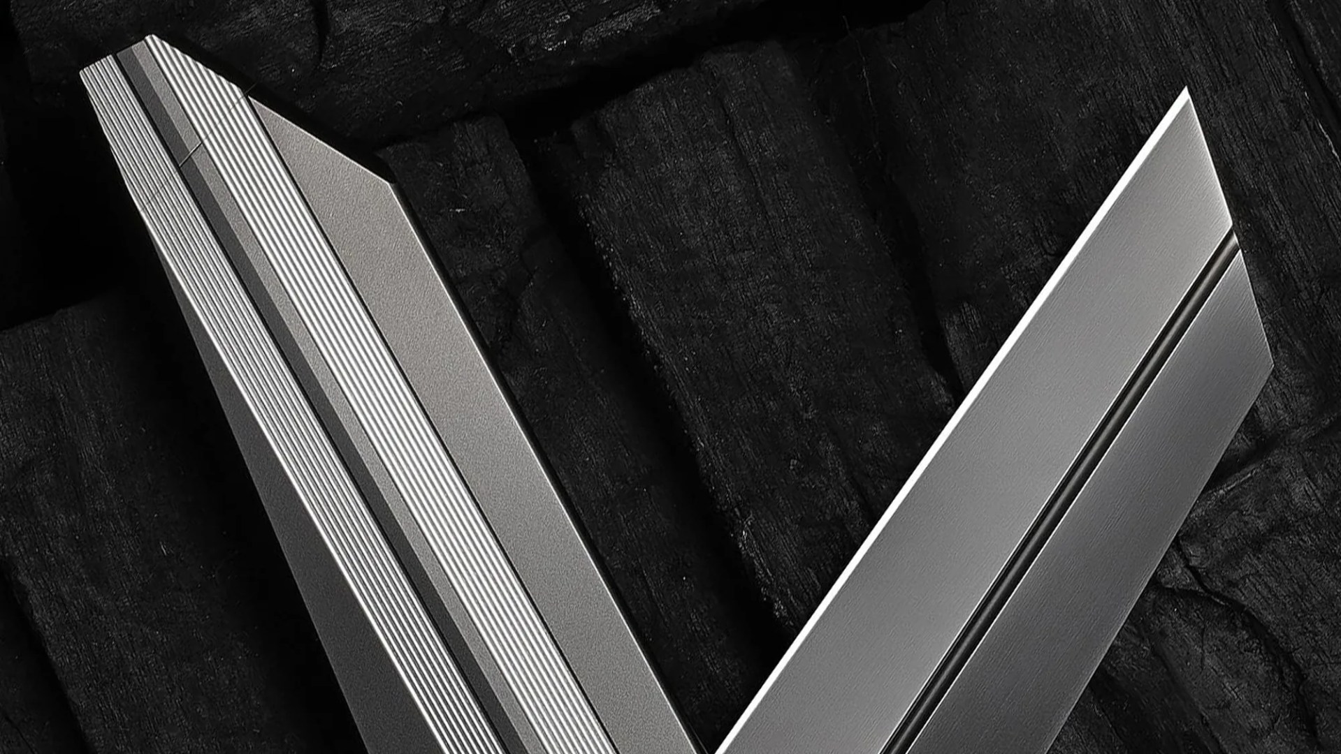 Close-up of two intersecting metallic silver blades with textured and smooth finishes on a dark textured background.
