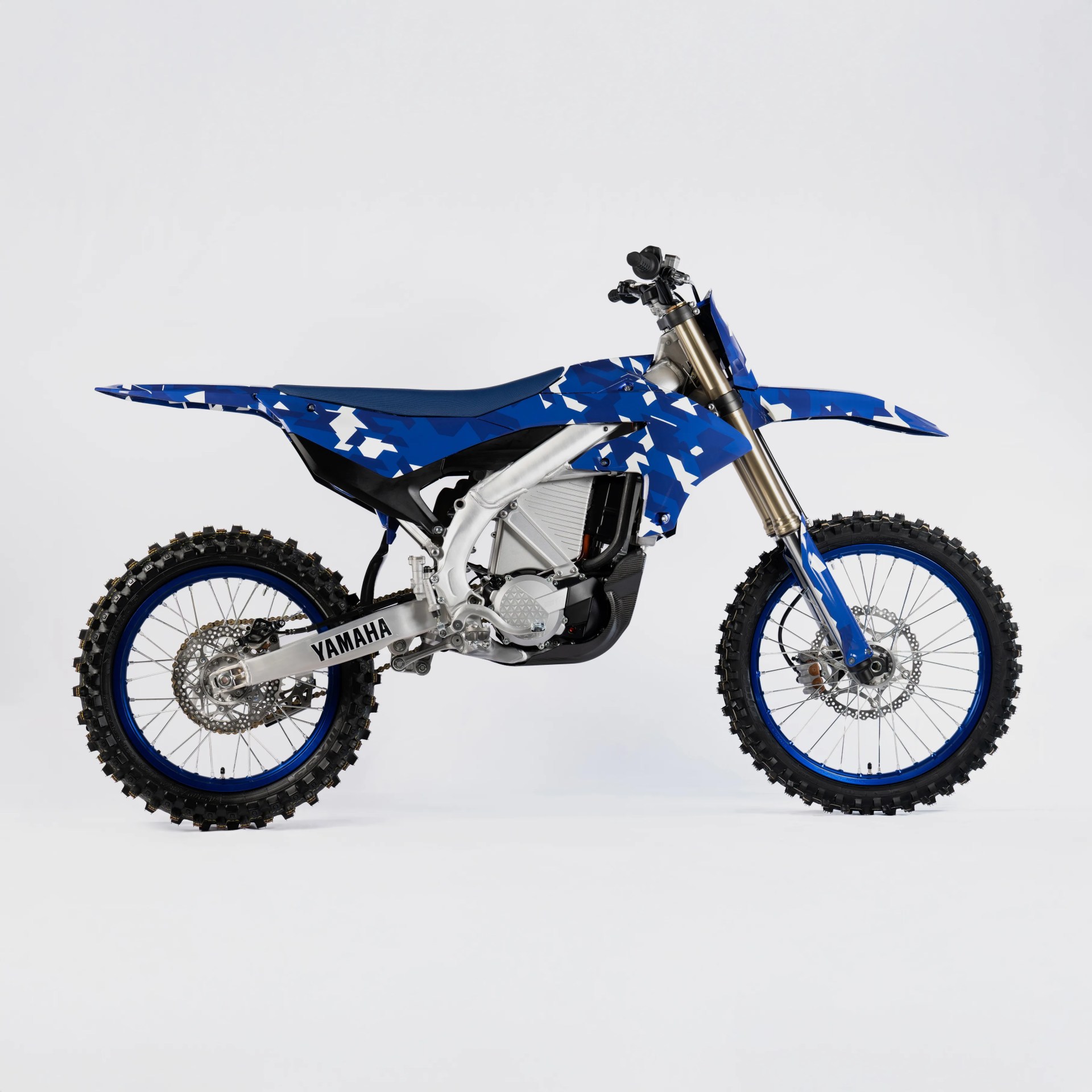 Blue and white camo Yamaha dirt bike with knobby tires and gold front forks on a white background.