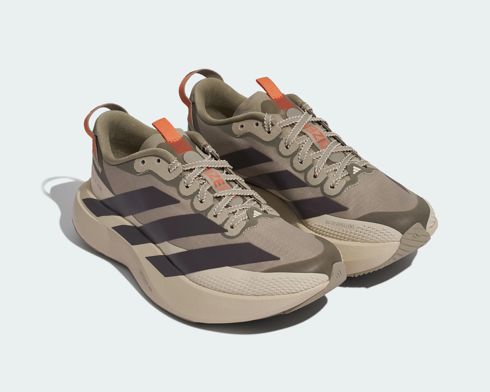 Pair of beige and olive green Adidas running shoes with black stripes and orange pull tabs.