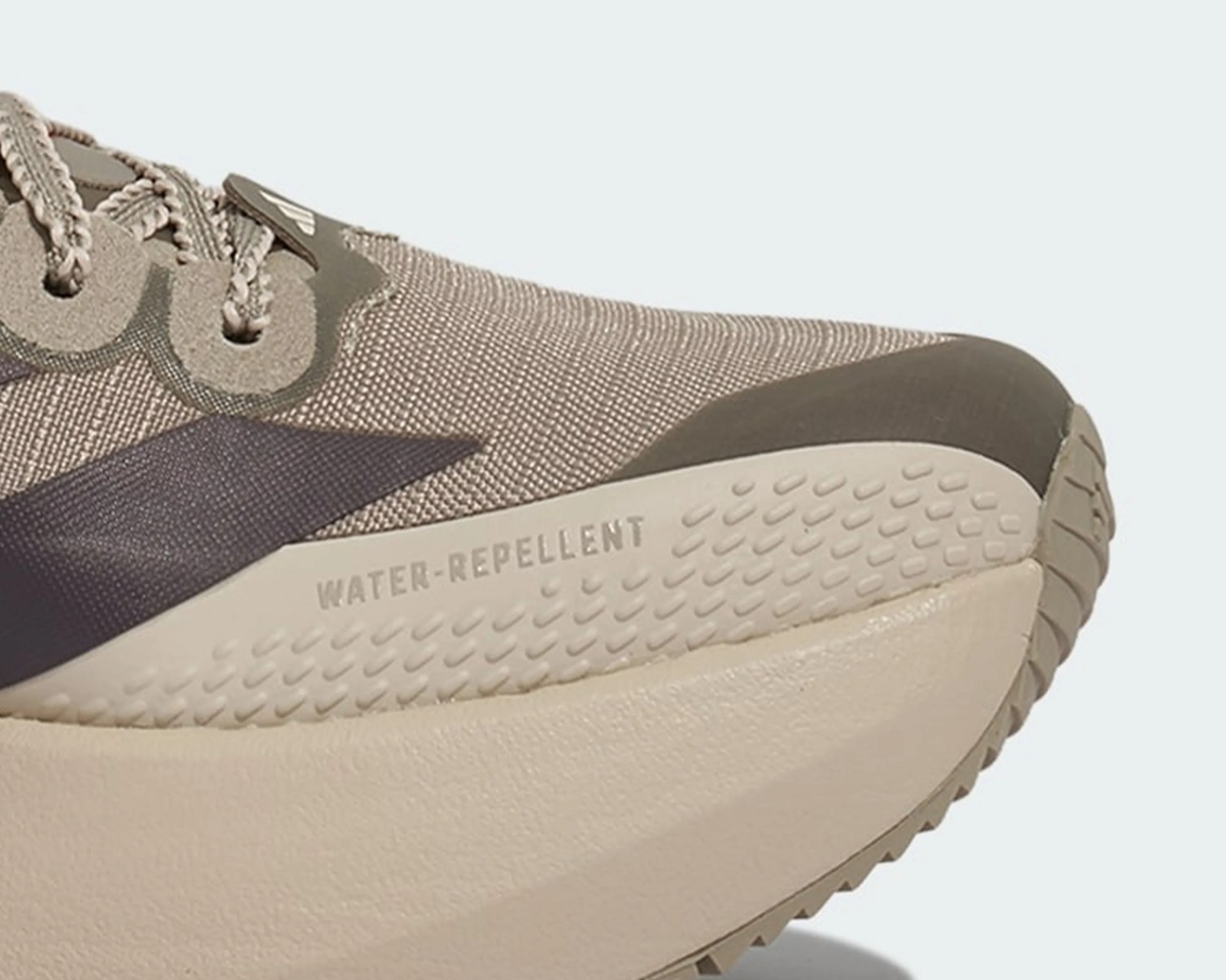 Close-up of beige and taupe water-repellent sneaker toe with textured sole and fabric upper.