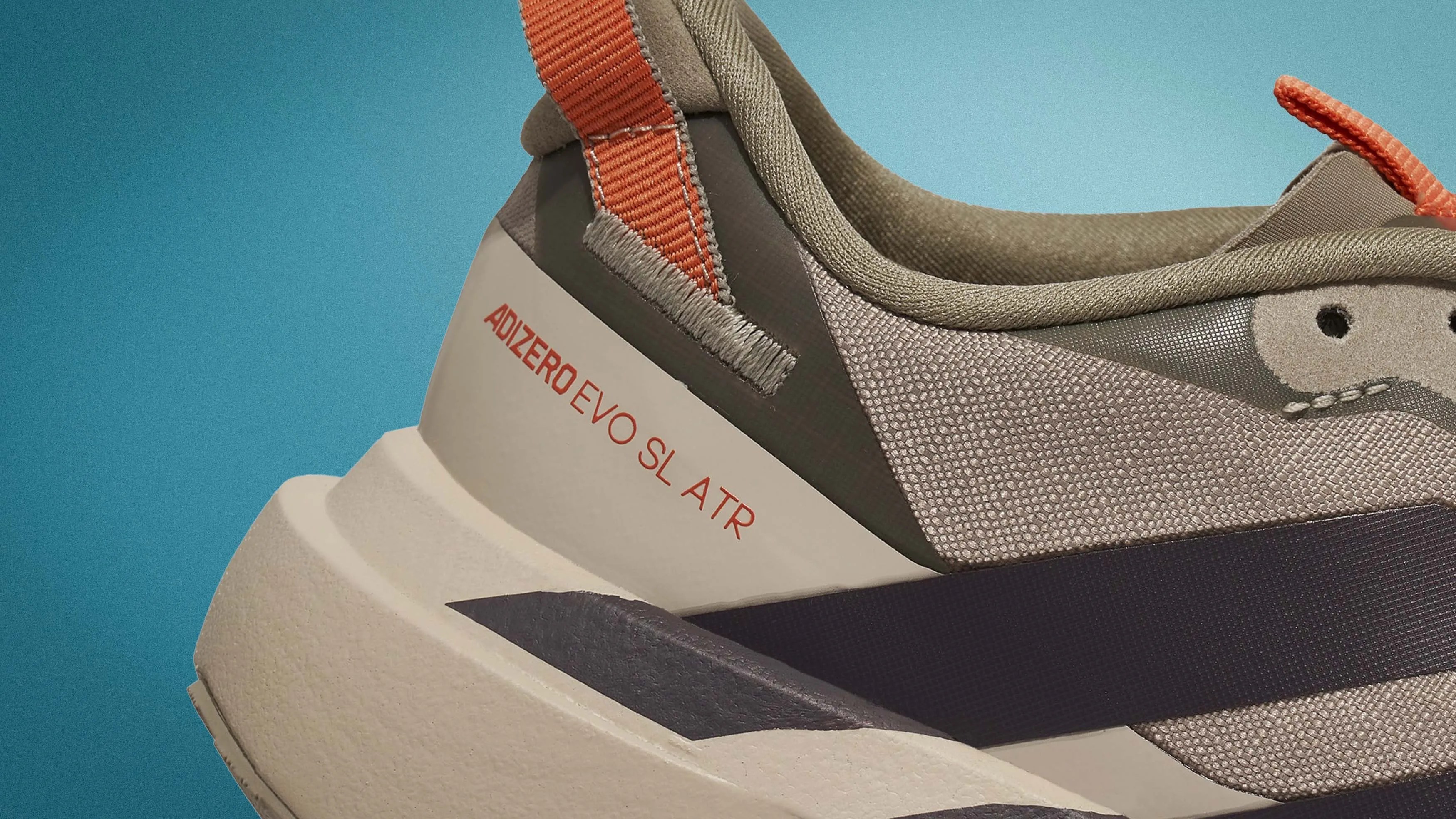 Close-up of the heel and side of a beige and orange Adidas Adizero Evo SL ATR sneaker with textured fabric and thick sole.