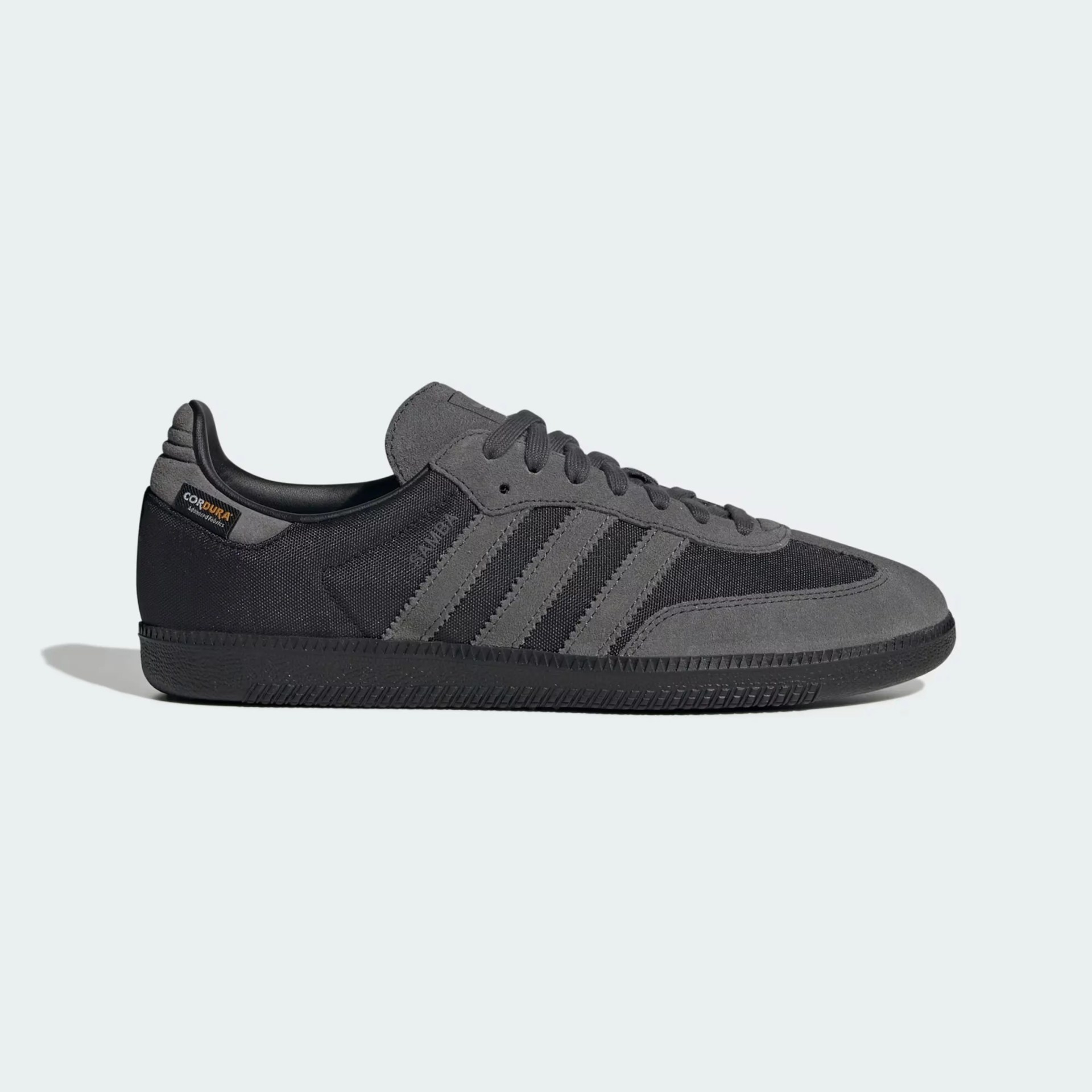 Low-top black and dark gray Adidas Samba sneaker with suede and Cordura fabric upper and black rubber sole.