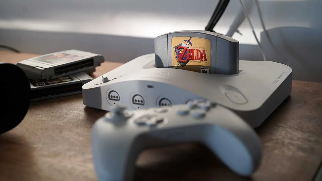 Gray Nintendo 64 console with The Legend of Zelda game cartridge inserted and a matching controller on a wooden surface.